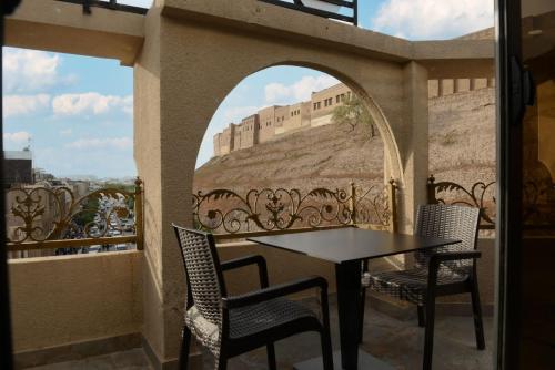 a balcony with a table and chairs and a wall at Syros Hotel Erbil City Center in Erbil