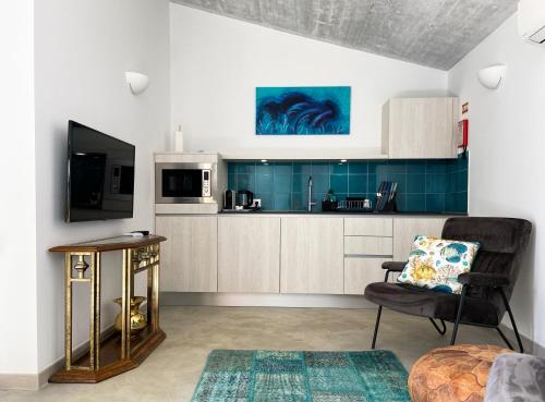 a kitchen with a couch and a chair and a television at B&B Alma do Campo in Olhão