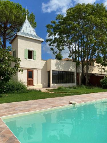 une maison avec piscine devant un immeuble dans l'établissement Maison d'hôtes ÔVillage, à Ouveillan