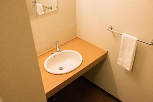 a bathroom with a white sink and towels at Guesthouse Sunline Beppu in Beppu