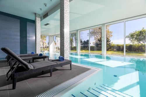 a house with a swimming pool with a reclining chair at Hotel Meridian in Chałupy