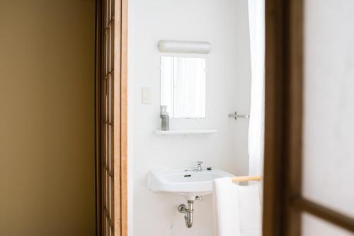 a bathroom with a white sink and a mirror at Guesthouse Sunline Beppu in Beppu