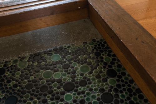 a tub filled with lots of green and black spheres at Guesthouse Sunline Beppu in Beppu