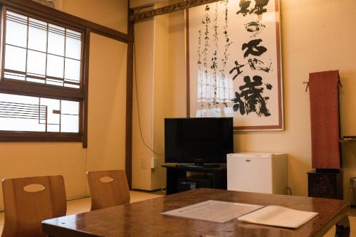 a room with a table and a tv and a table and chairs at Guesthouse Sunline Beppu in Beppu