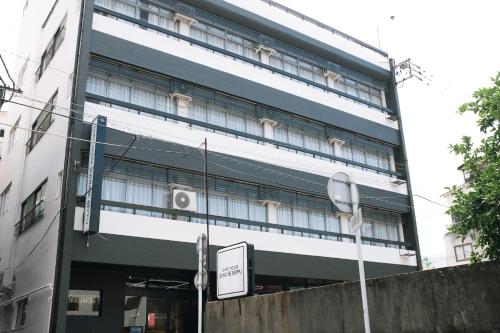 a tall building with a sign in front of it at Guesthouse Sunline Beppu in Beppu