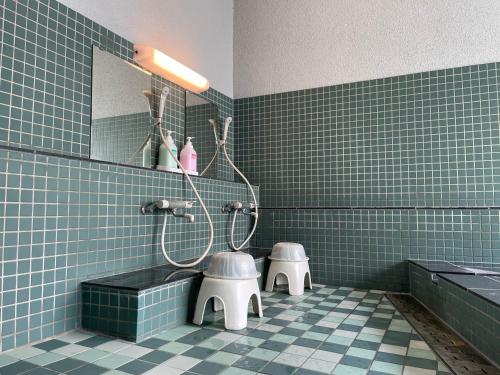 a blue tiled bathroom with two toilets and a mirror at Guesthouse Sunline Beppu in Beppu