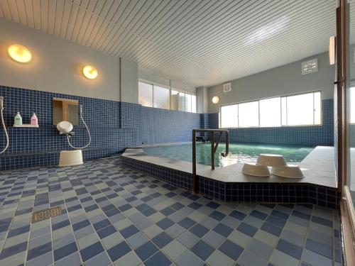 uma grande casa de banho com uma piscina com azulejos azuis em Guesthouse Sunline Beppu em Beppu