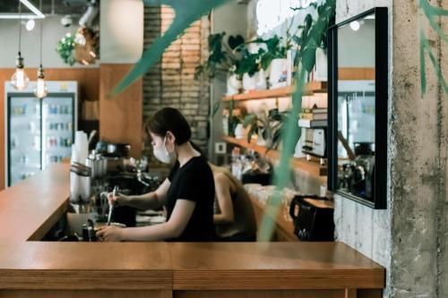 a woman behind the counter of a coffee shop at Guesthouse Sunline Beppu in Beppu