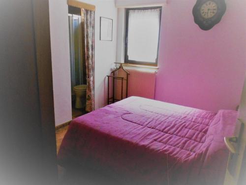 una camera rosa con un letto con una coperta rosa di Les VENDANGEURS a Niedermorschwihr