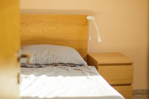 a bed with a wooden headboard next to a night stand at Vendvidéki Pihenőházak in Felsőszölnök
