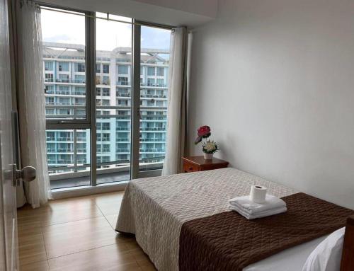 um quarto com uma cama e uma grande janela em Azure Urban Resort A1 balcony near Mall airport em Manila