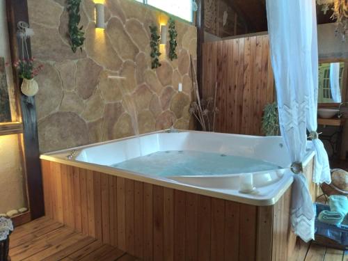 a large tub in a room with a stone wall at Pualy Resort & Spa in Belén de Escobar
