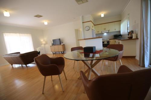 a living room with a glass table and chairs at Wagga Showground Villas in Wagga Wagga