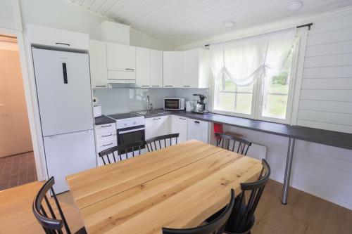 uma cozinha com uma mesa de madeira e cadeiras em Lomaperkkiö Cottages em Kajaani