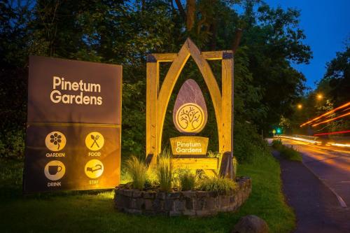 un cartello per giardinieri di pfinity sul lato di una strada di Pinetum Garden Cottages a St Austell