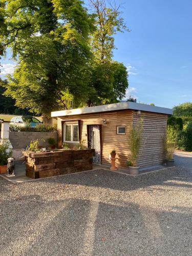 a small wooden cabin with a porch and a tree at Die Pilgerbox, Tiny House trifft Urlaub, optional mit Sauna und Whirlpool in Dahlem