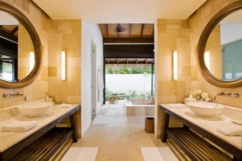 ein Badezimmer mit zwei Waschbecken und zwei Spiegeln in der Unterkunft COMO Maalifushi - Partner Travels FREE for 7 Nights or More in Maalifushi