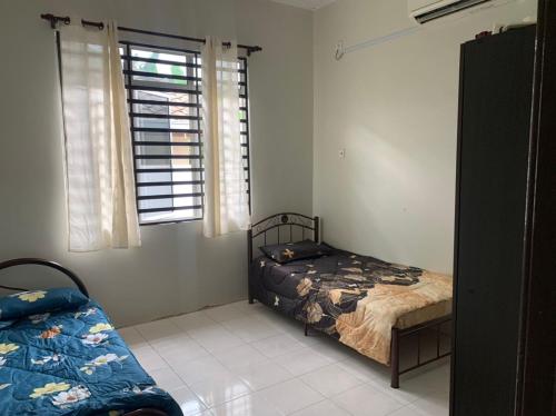 een slaapkamer met 2 bedden en een raam bij Homestay Maryam in Lumut