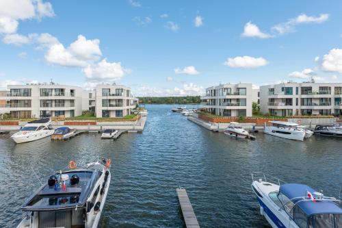 a group of boats docked in a river with buildings at Sol Marina Riverview with free Parking & SPA additional by Downtown Apartments in Wiślinka