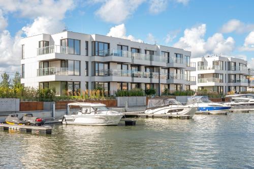 a large white building with boats docked in a marina at Sol Marina - Pool, SPA, Wellness, Riverview & Parking by Downtown Apartments in Wiślinka