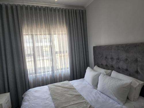 a bedroom with a bed with a large window at Sarona city Habitat Alpha apartments C202 Gaborone in Gaborone