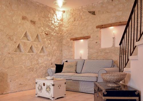 uma sala de estar com um sofá e uma parede de pedra em Olive Coast Suites em Palekastron