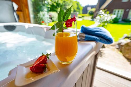 a glass of orange juice and a plate of strawberries at Ferienhaus Gesoeders Hus in Sankt Peter-Ording