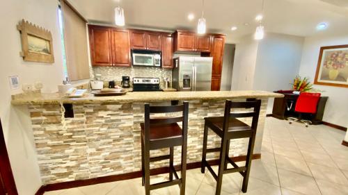 a kitchen with a counter and two chairs at a bar at Monte Carlo Luxury Condominiums in Jacó
