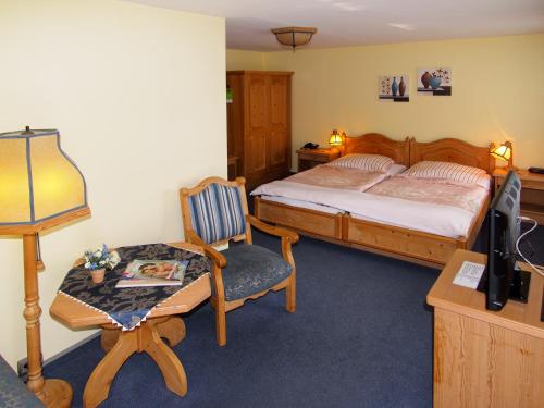 ein Schlafzimmer mit einem Bett, einem Stuhl und einem Schreibtisch in der Unterkunft Hotel Grüner Baum in Genthin