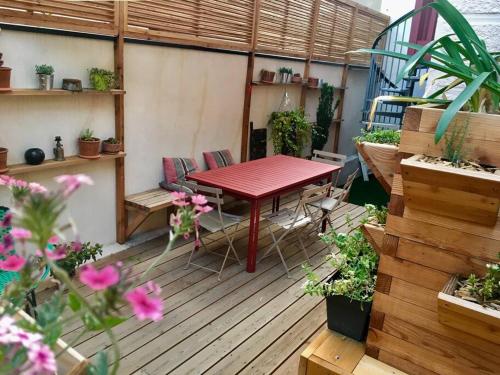 eine Terrasse mit einem roten Tisch und einigen Pflanzen in der Unterkunft Maison de caractère en centre ville in Vichy