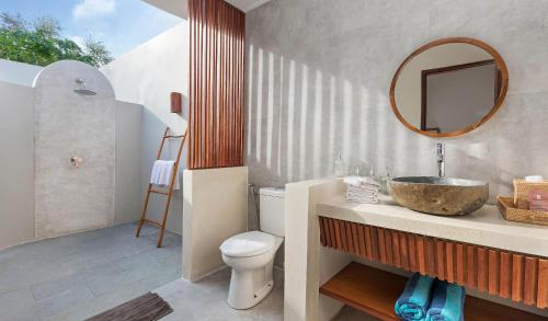 uma casa de banho com um lavatório, um WC e um espelho. em KU Villas em Kuta Lombok