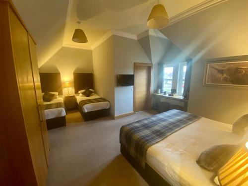 a hotel room with two beds and a window at Ravelston House in Musselburgh