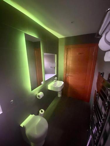 a green bathroom with a toilet and a sink at Ravelston House in Musselburgh