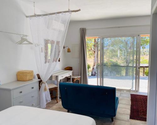 a bedroom with a bed and a desk and a window at La Rústica en Viñuela, piscina privada in Viñuela