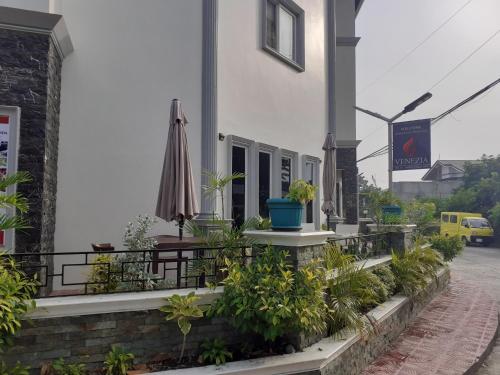a building with a patio with plants and an umbrella at Venezia Suites Hotel Iloilo in Iloilo City