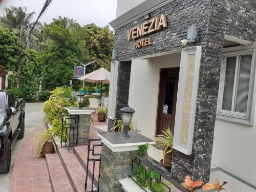 a restaurant with a sign on the side of a building at Venezia Suites Hotel Iloilo in Iloilo City