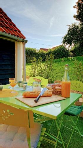- une table de pique-nique avec de la nourriture et une bouteille de jus d'orange dans l'établissement Le cottage du Marais., à Houlle