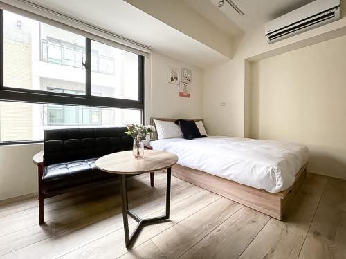 een slaapkamer met een bed, een tafel en een bank bij 旅行家 Affetto Hostel in Taichung