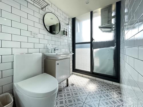 a white bathroom with a toilet and a mirror at 旅行家 Affetto Hostel in Taichung