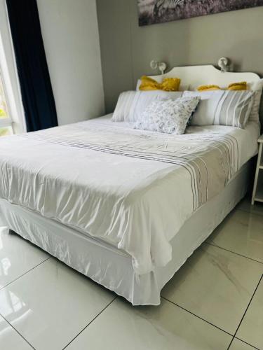 a bed with white sheets and pillows on it at Seagull Beach resort flat number 313 in Margate