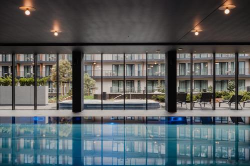 a swimming pool in a building with a building in the background at BELMONTE Hotel Krynica-Zdrój in Krynica Zdrój