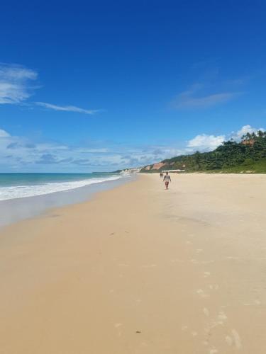 a person walking on a sandy beach near the ocean at 4 Elementos Guest House in Arraial d'Ajuda