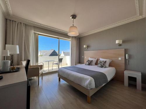a bedroom with a bed and a desk and a window at Hôtel Ker-Noyal Quiberon Plage in Quiberon