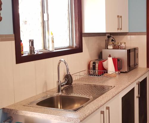 - un comptoir de cuisine avec évier et four micro-ondes dans l'établissement Allora House Kalgoorlie, à Kalgoorlie