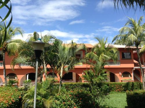 an orange building with palm trees in front of it at Apartotel Flamboyant in Jacó