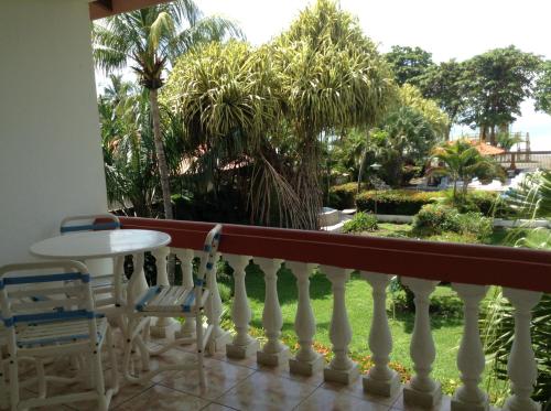 a balcony with a table and chairs and a garden at Apartotel Flamboyant in Jacó
