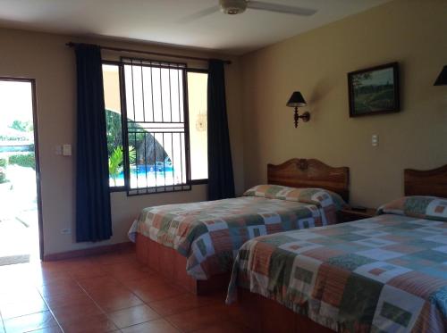 a bedroom with two beds and a large window at Apartotel Flamboyant in Jacó