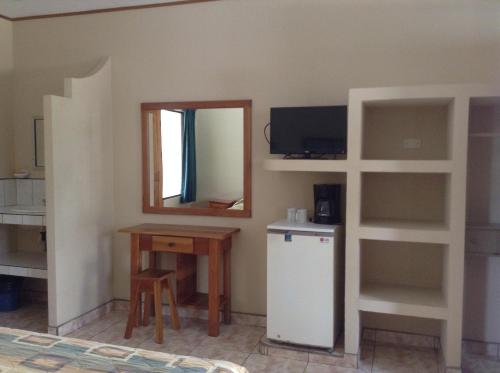 a kitchen with a table and a mirror and a refrigerator at Apartotel Flamboyant in Jacó