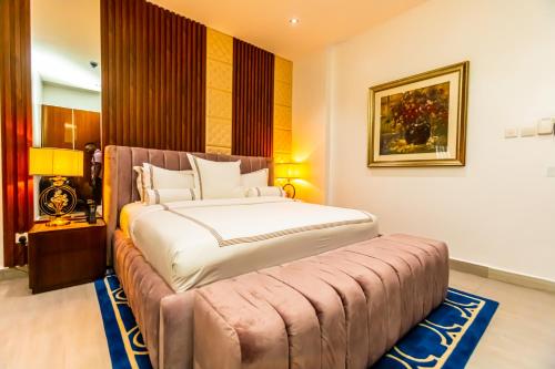 a bedroom with a large bed with a bench around it at Isglo Hotels Ikoyi in Lagos