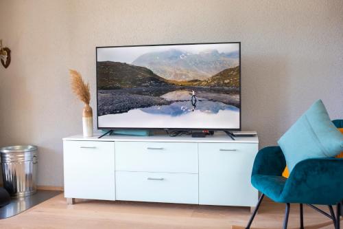 a living room with a tv on a white cabinet at Traumhafte Sonnenresidenz mit Berg- und Seeblick in Amden